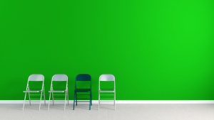 four folding chairs set against green wall, three chairs are silver and one is black
