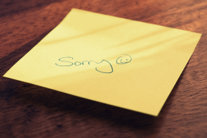 word sorry and a smiley face written on a post-it not to indicate a less-than-great apology
