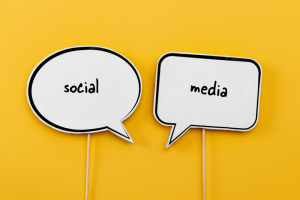 words social and media in individual speech bubbles over a yellow background indicating a conversation like the one you should have on social media